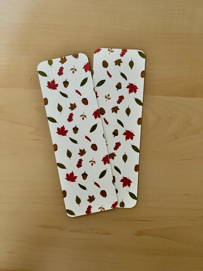 Two rectangular bookmarks with autumn leaf pattern on a wooden surface