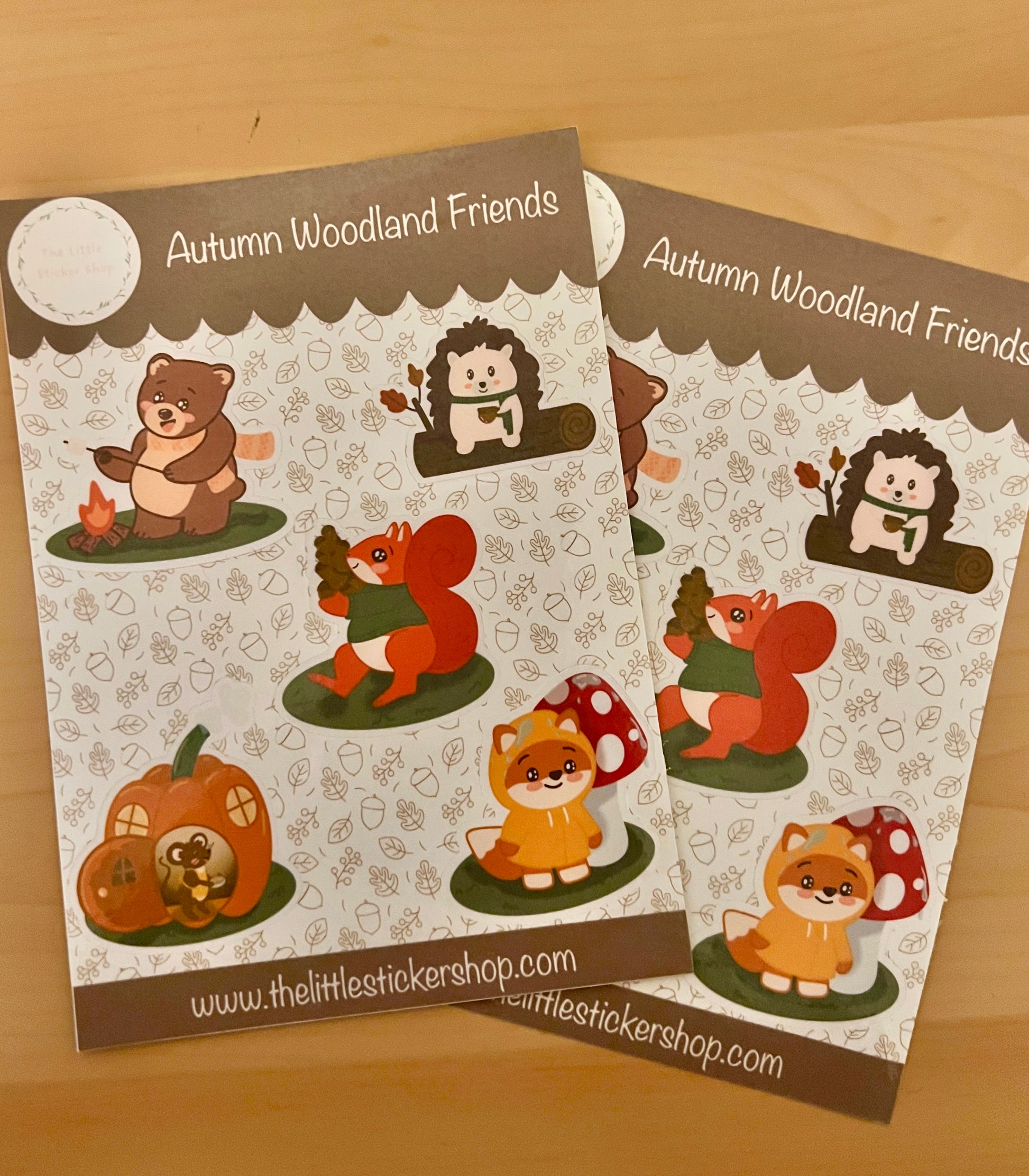 2 Sticker sheets with 5 cute character animals - a bear roasting a marshmallow over a campfire, a hedgehog drinking a hot drink on a log - a squirrel carrying a mountain of acorns, a fox in a raincoat, and a mouse in a pumpkin house.