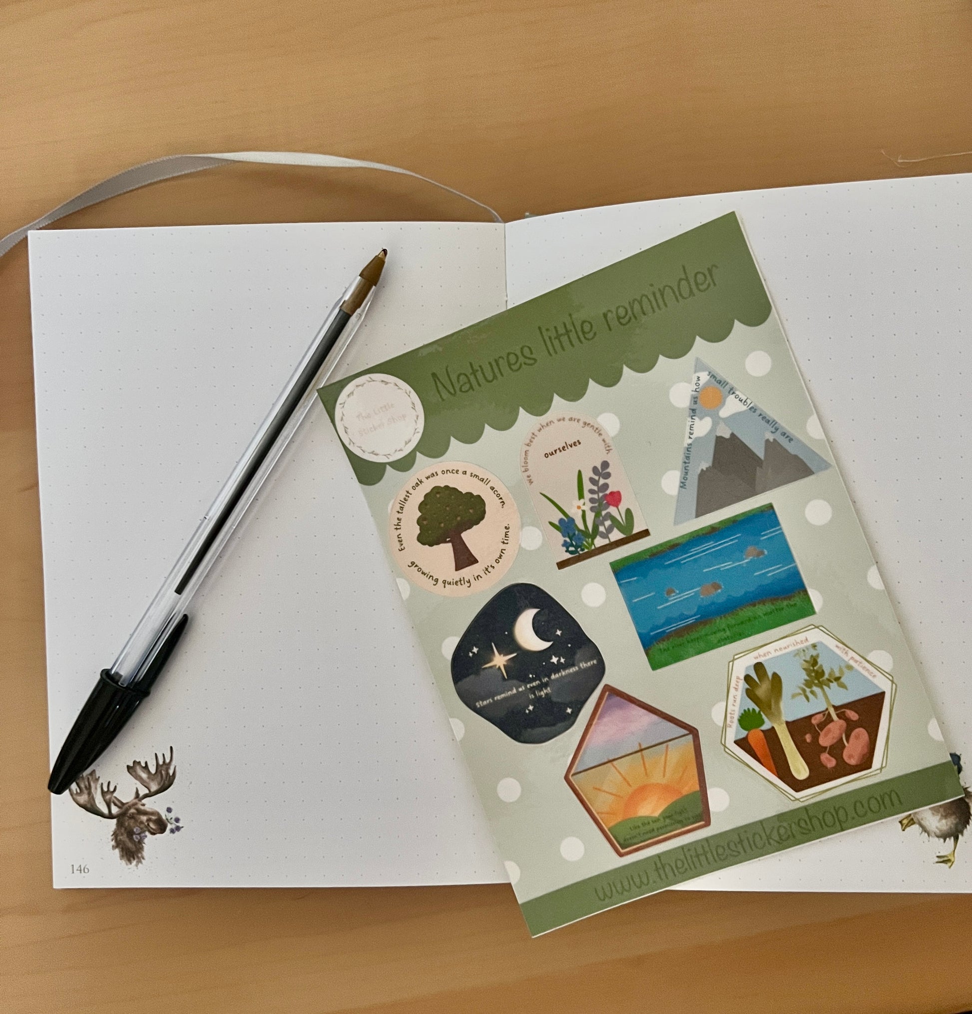Set of nature-themed sticker sheet on a notebook with a pen on a wooden surface