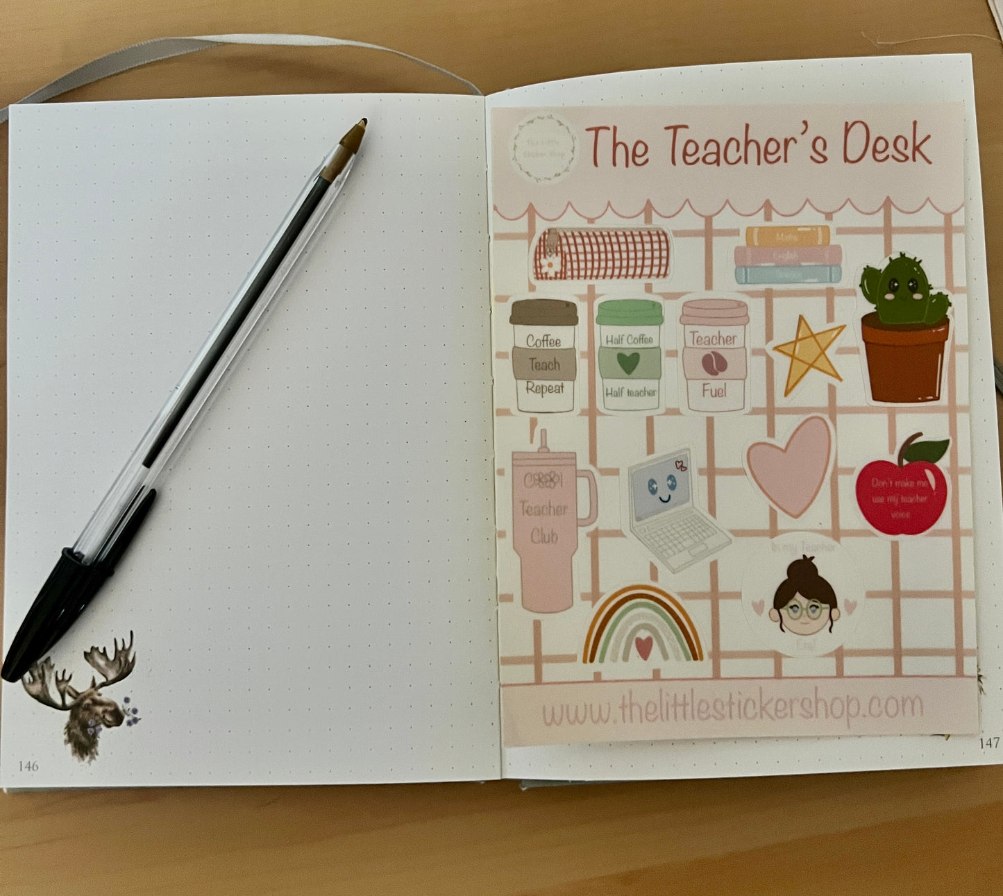 Open notebook with stickers from 'The Teacher's Desk' on a wooden surface