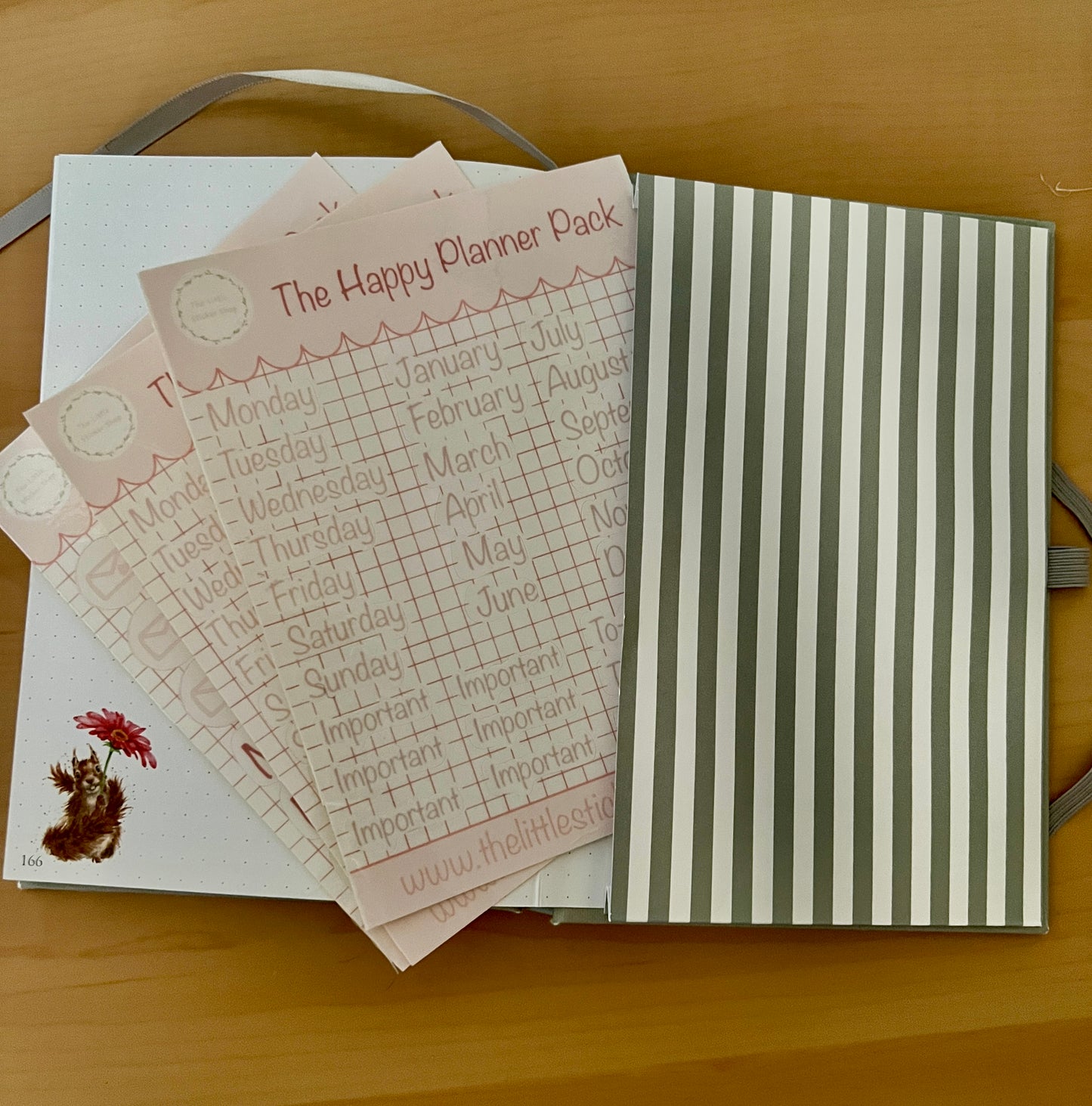 Happy Planner pack with planner sheets in a journal on a wooden surface
