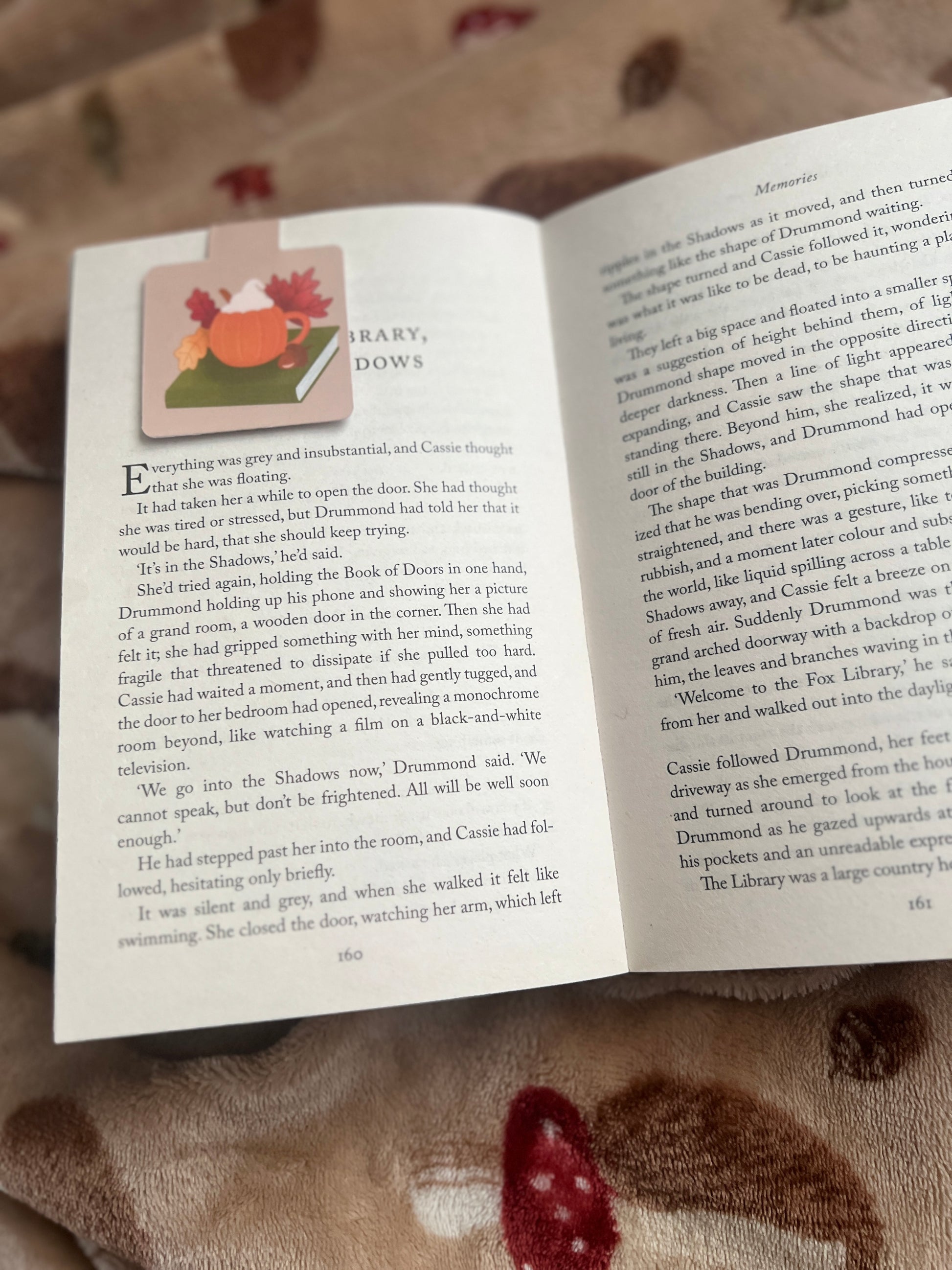 Open book with a magnetic bookmark featuring a pumpkin mug on a book on a textured fabric background