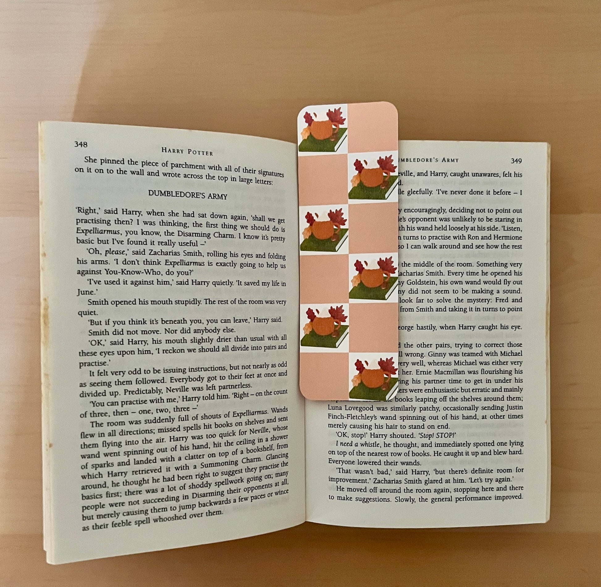 Book with a decorative bookmark featuring cartoon pumpkin cup on a wooden surface
