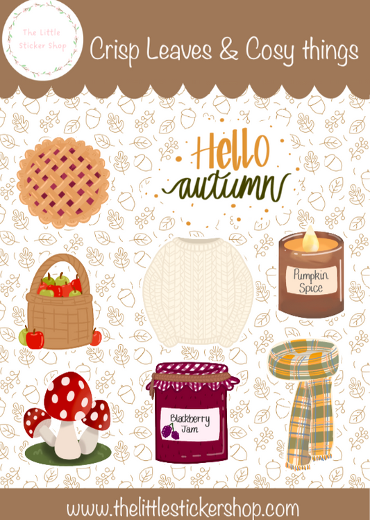 Autumn themed sticker sheets laid on a table, includes illustrations of a knitted jumper, scarf, pumpkin spice candle, blackberry jam, mushroom, apples in a basket, cherry pie and 'Hello Autumn' text. 